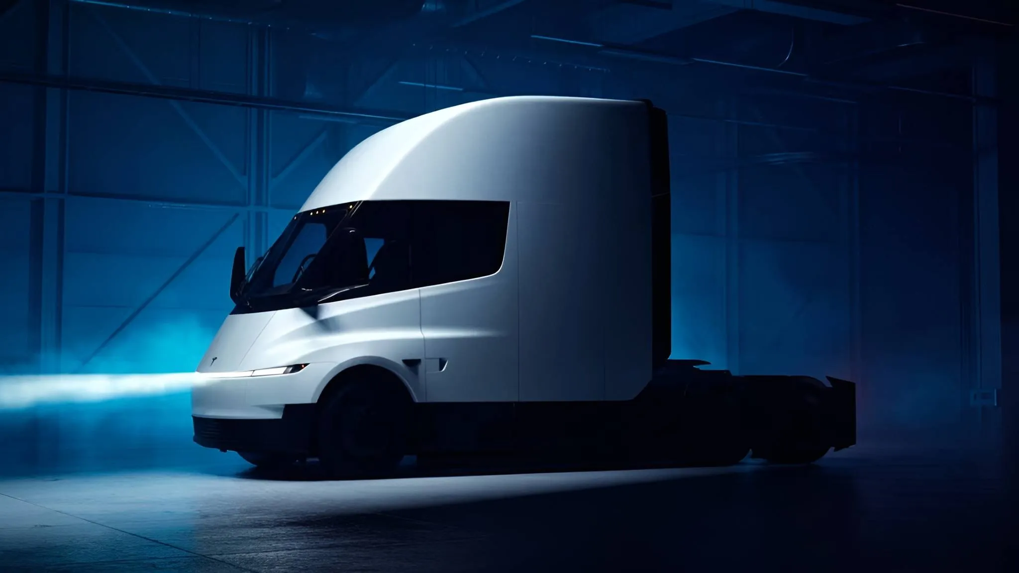 il tesla semi, il camion elettrico creato da tesla con sfondo scuro e di colorazione bianca in posizione laterale e i fari accesi