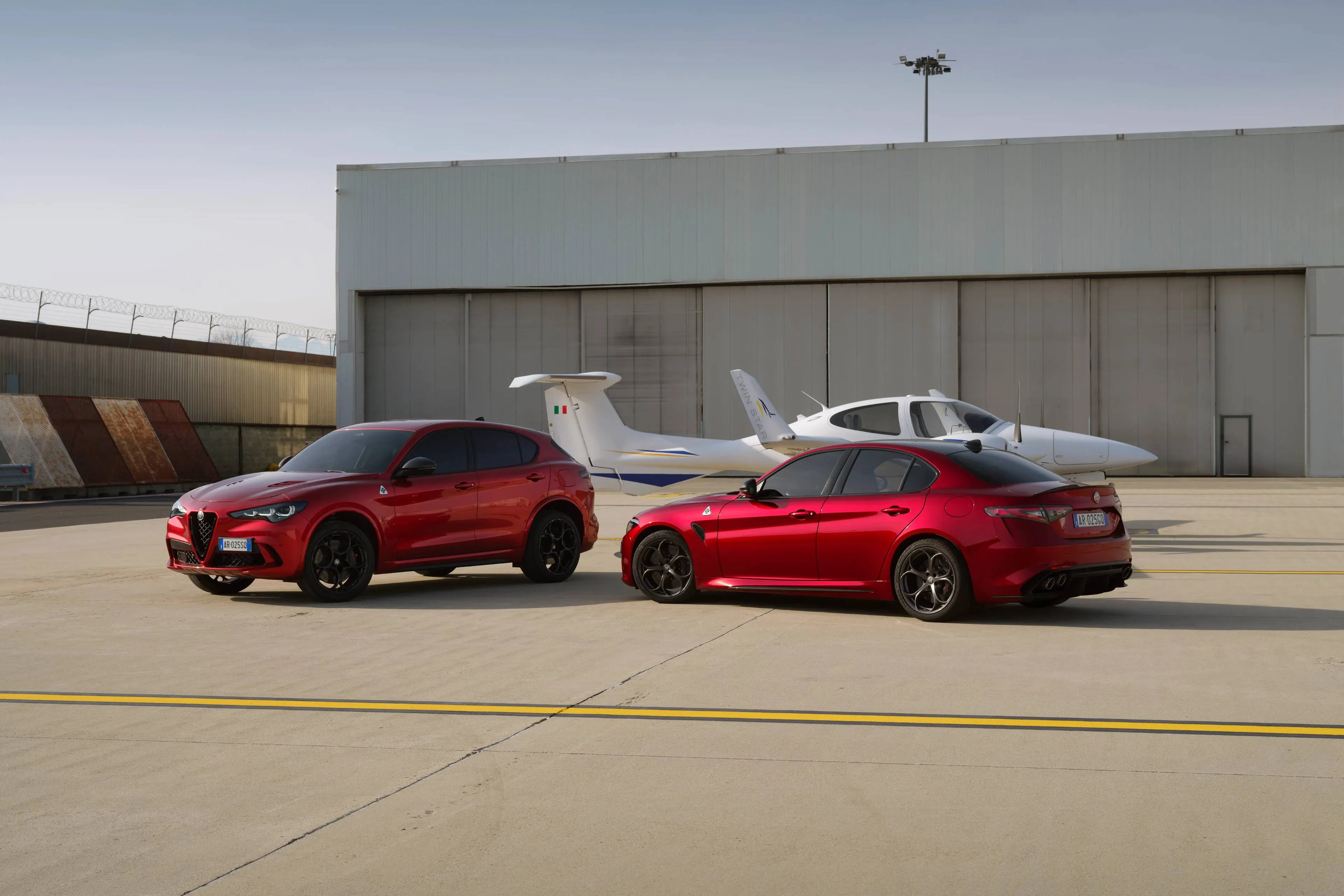 Le Alfa Romeo Giulia e Stelvio Quadrifoglio riprese in un aeroporto con dietro un aereo cessna