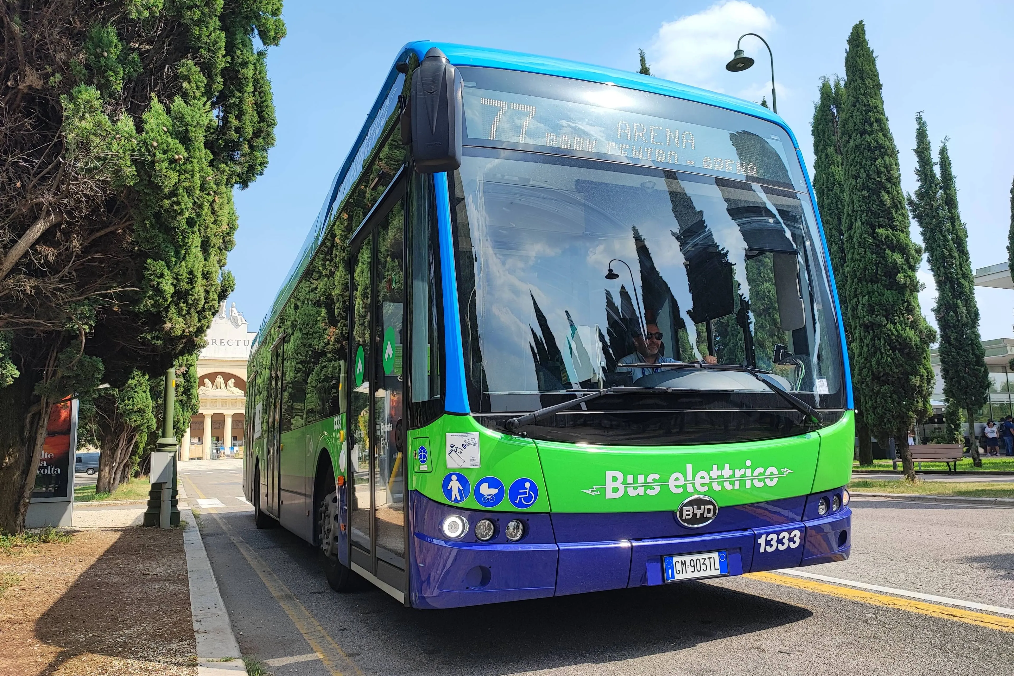 BUS di colore verde e blu della marca BYD in collaborazione con ATV di Verona su una strada tra due file di alberi