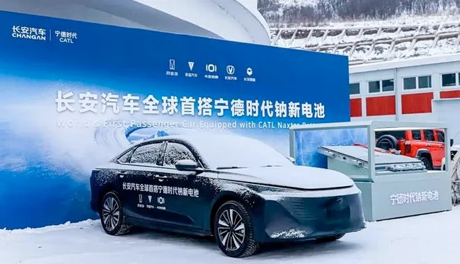 Una berlina Changan nera coperta di neve davanti a un banner blu che annuncia la prima auto al mondo con batteria al sodio CATL. A destra, una teca espone il pacco batterie tecnologico in un ambiente invernale.