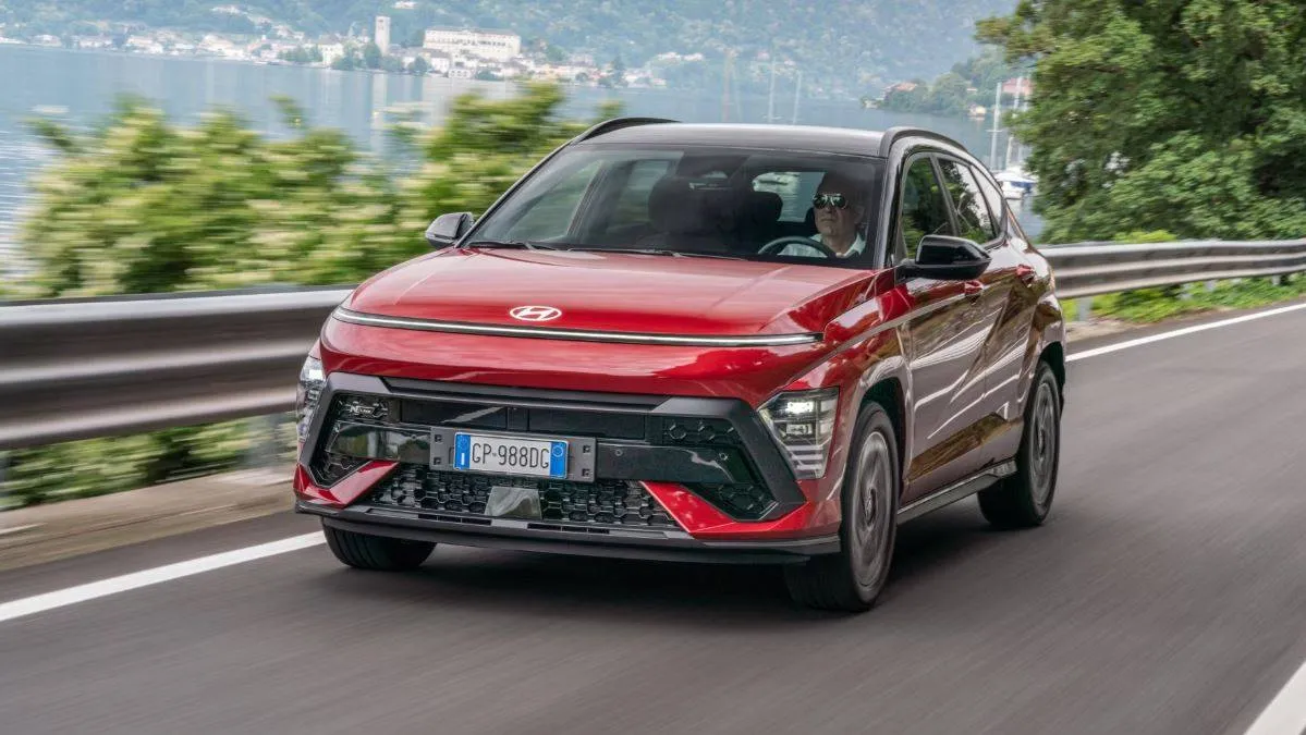 Hyundai Kona N Line con frenata rigenerativa. Auto di colore rosso in dinamica su una strada con un lago sullo sfondo