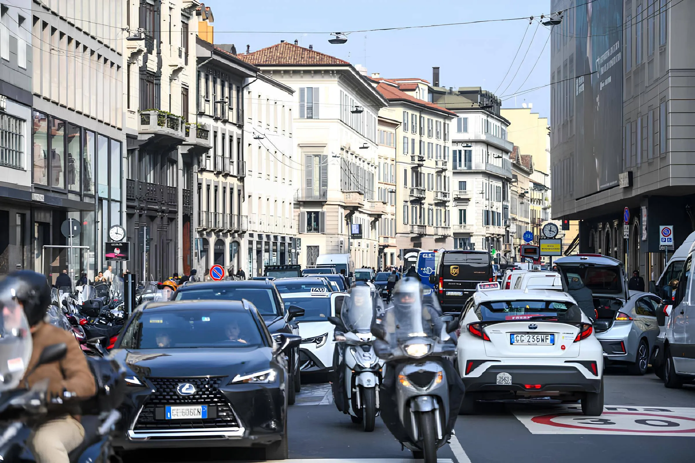 L'immagine raffigura una strada trafficata, probabilmente in Italia. Sullo sfondo si possono notare dei palazzi bianchi.