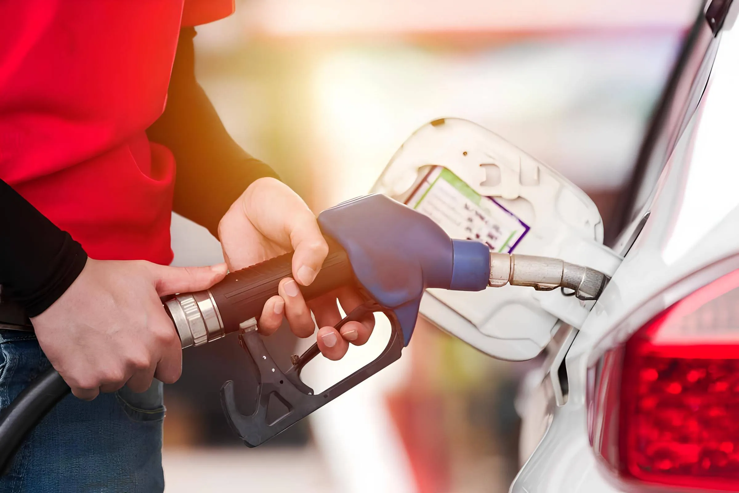 Nell'immagine si vede una persona che è impegnata a fare rifornimento ad un auto