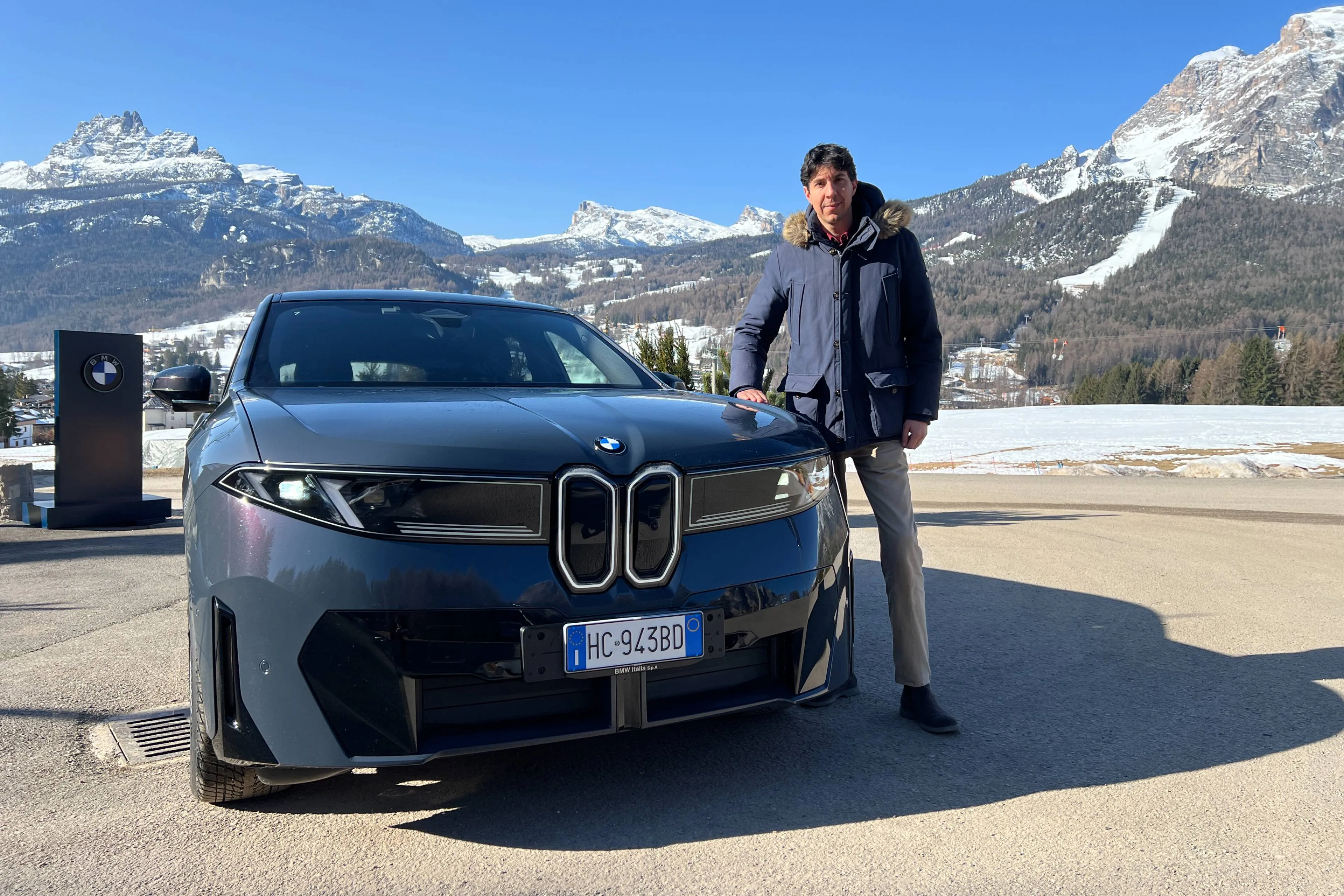 Federico Ferrero al fianco della bmw ix3 di colore blu grigio con sfondo montagne