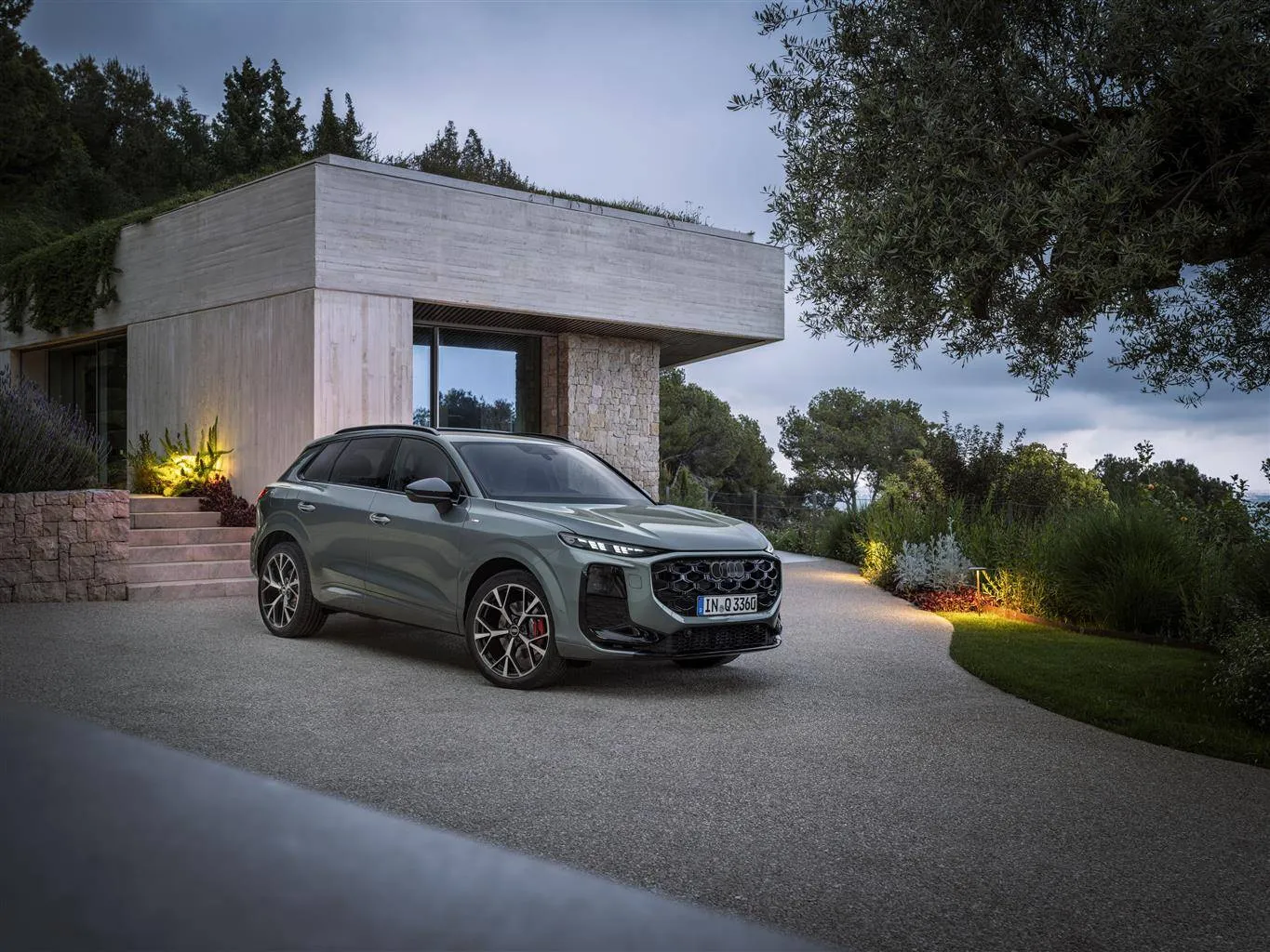 Audi Q3 tdi da 193 CV di colore grigio parcheggiata di muso davanti a una casa moderna