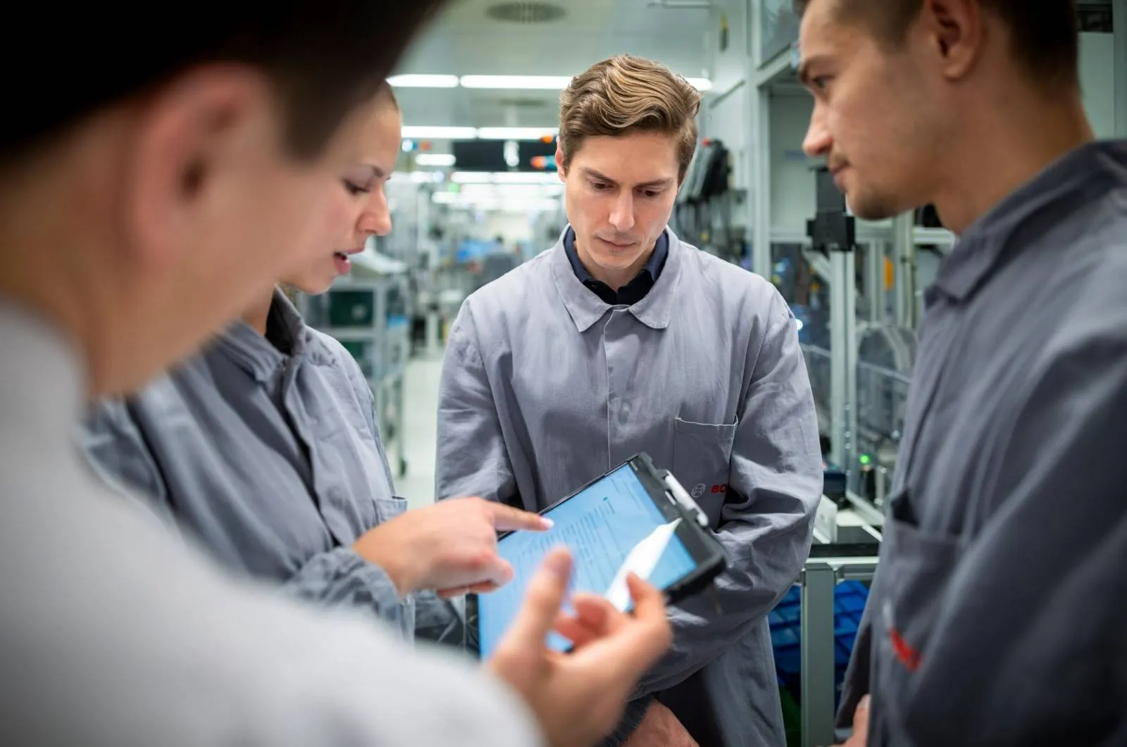 bosch-ai alcuni dipendenti bosch vestiti con tute grigie davanti a un tablet