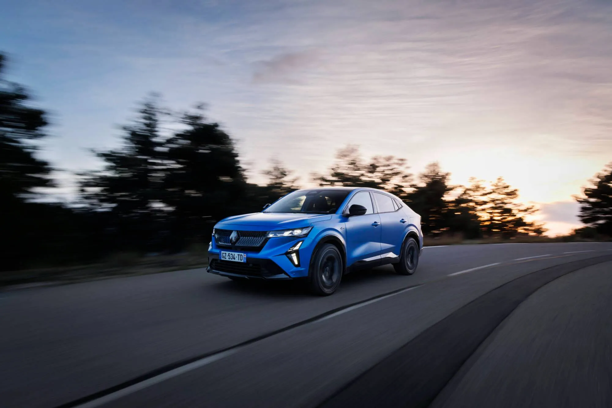 Renault_Rafale_E-Tech_4x4_300_ch_-_Atelier_Alpine_-_Bleu_Sommet dinamica al tramonto su strada