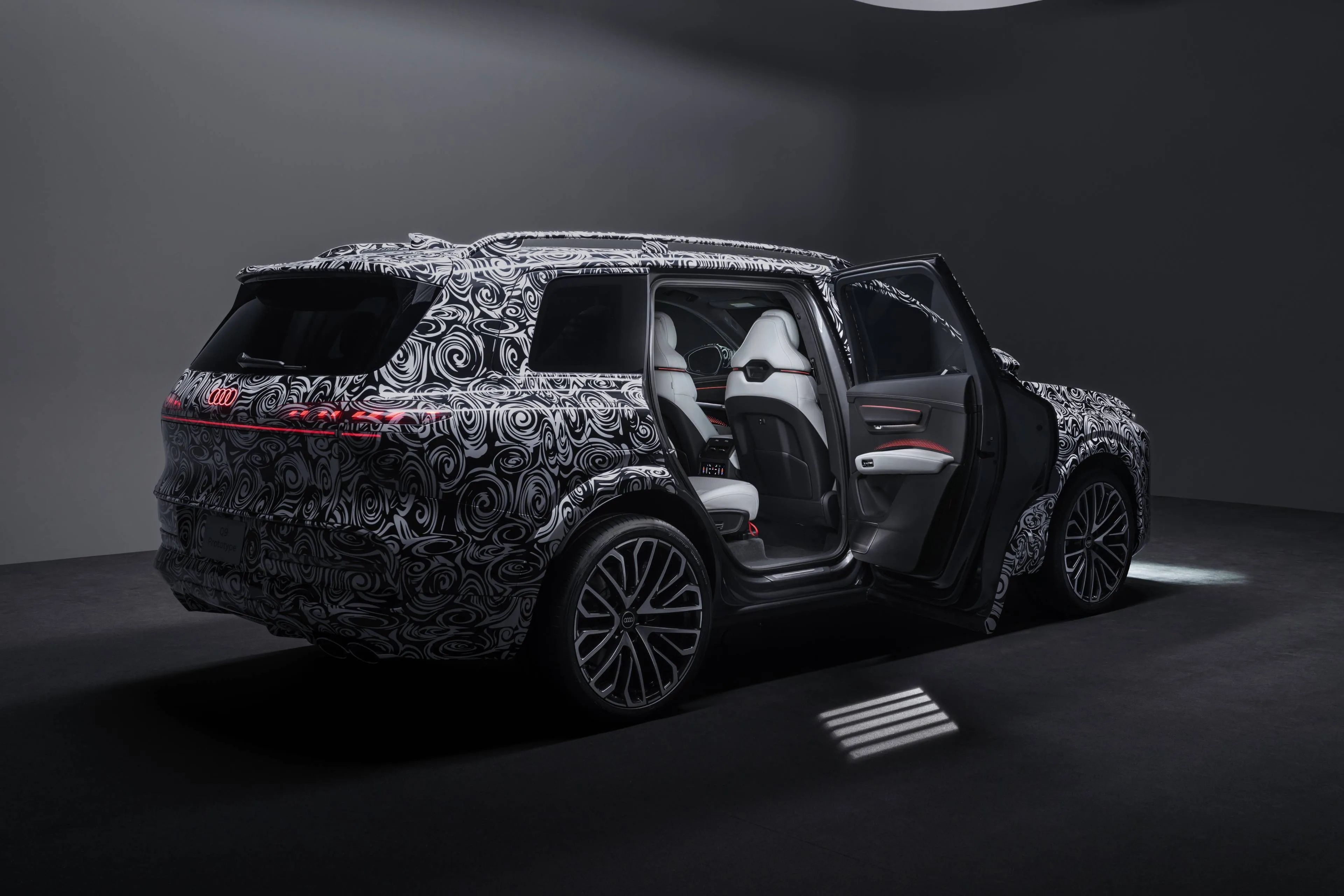 Audi Q9 vista da dietro interamente camuffata con la portiera posteriore aperta