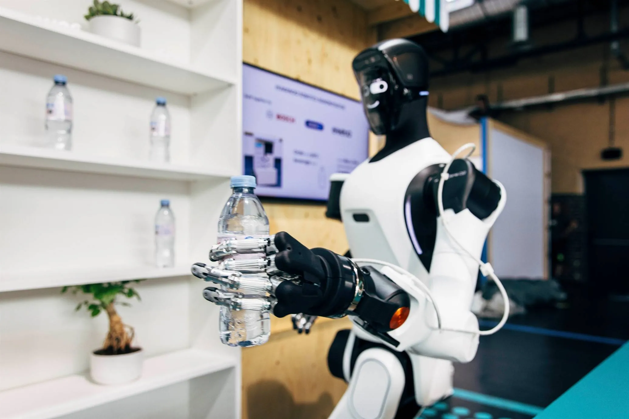 robot umanoide tiene in mano una bottiglietta d'acqua