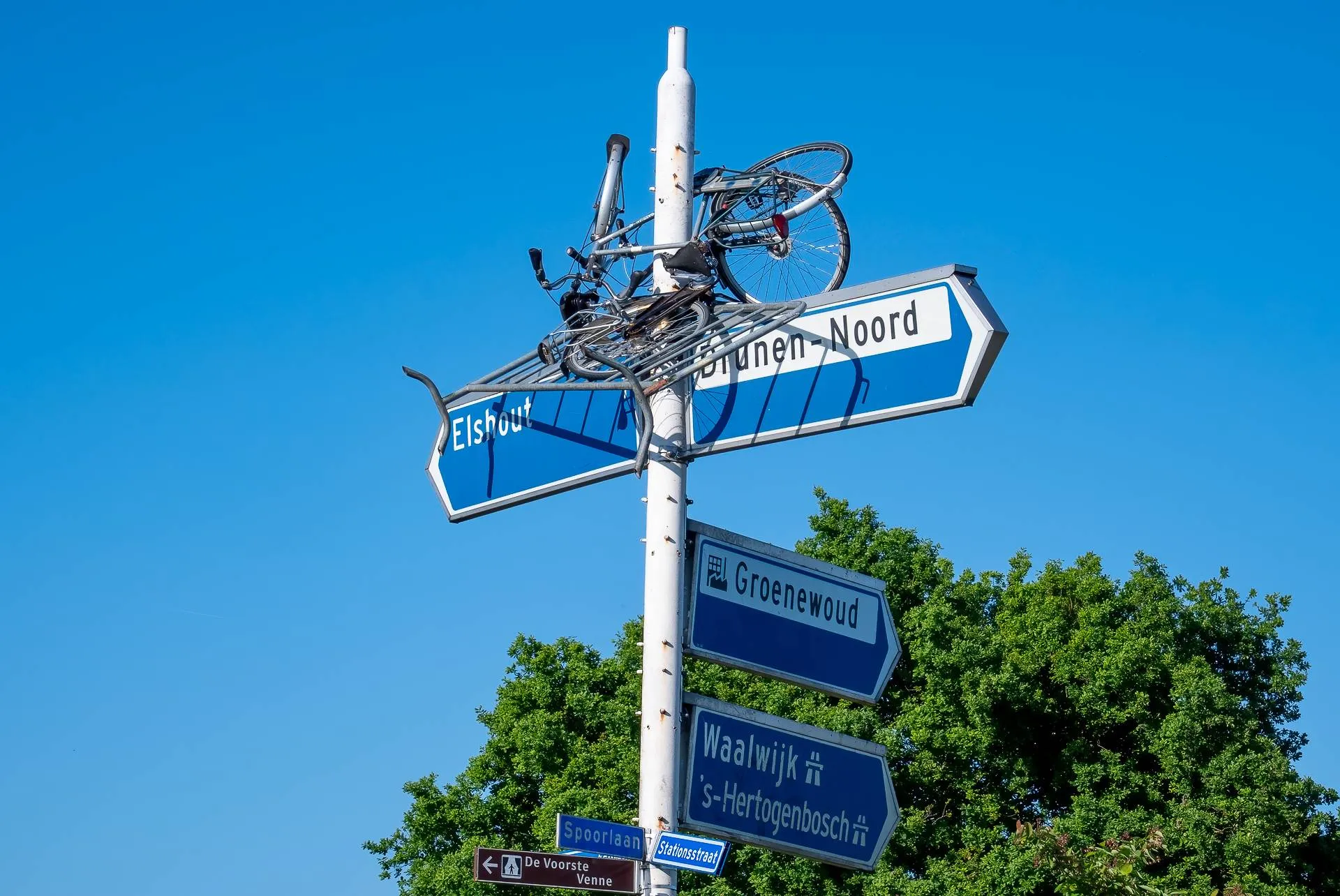 Fietsen en dranghek bovenin ANWB-paal in Drunen