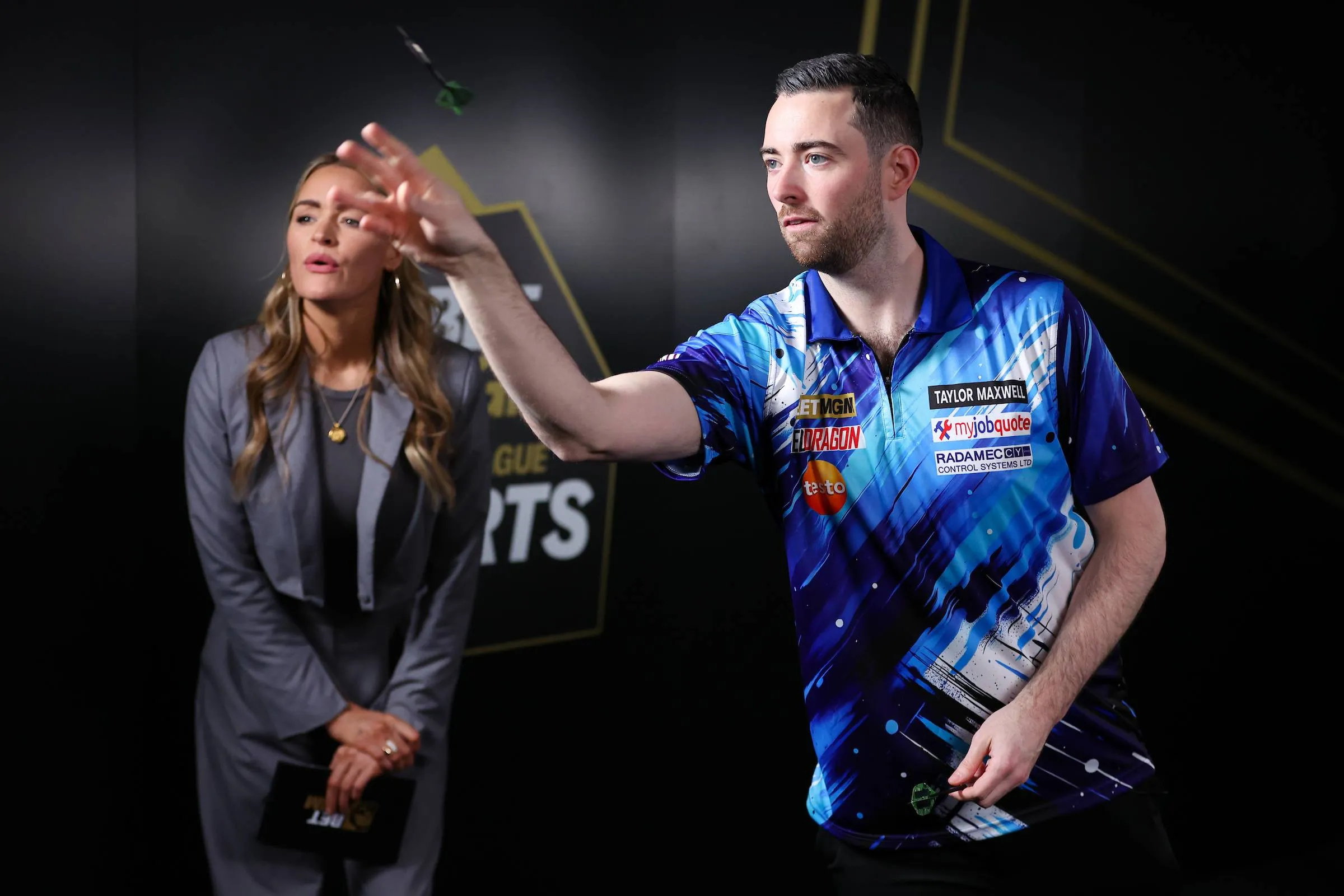 Luke Humphries takes on BetMGM's Eye of the Needle challenge as presenter Laura Woods watches on