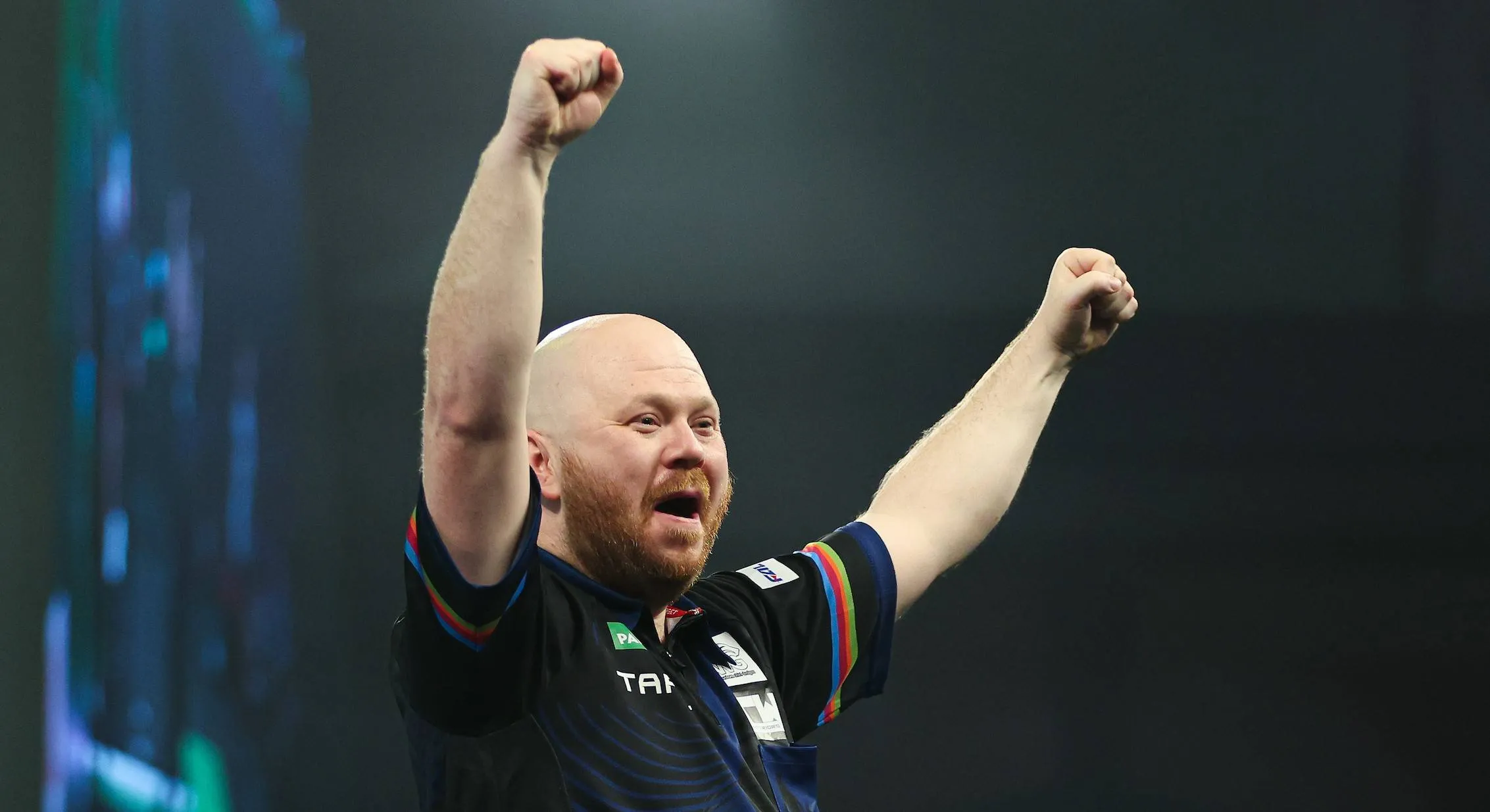 Justin Hood juichend op het podium in Alexandra Palace