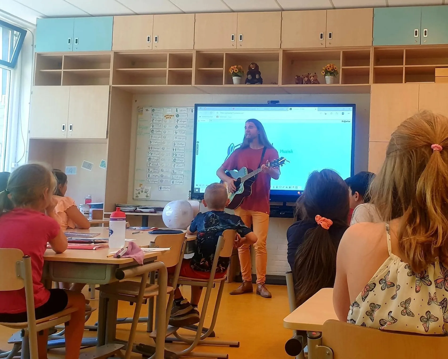showkorpsen irene trakteren basisscholen op muziekles foto beschrijving meester dennis met gitaar voor de klas