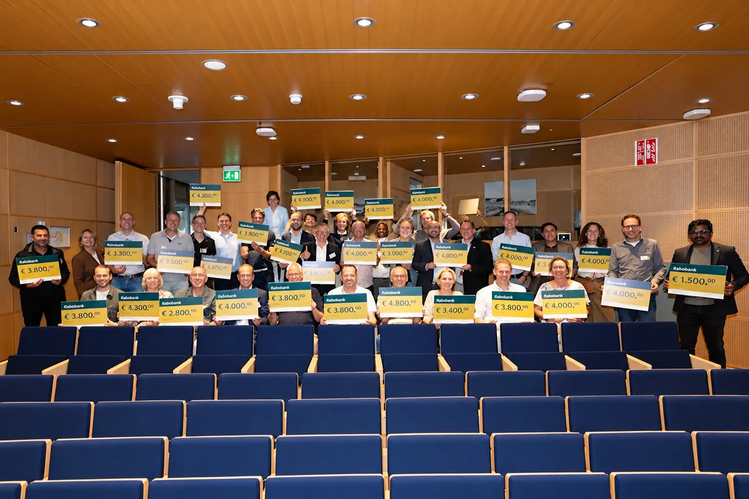Groepsfoto met donatiecheques in het auditorium