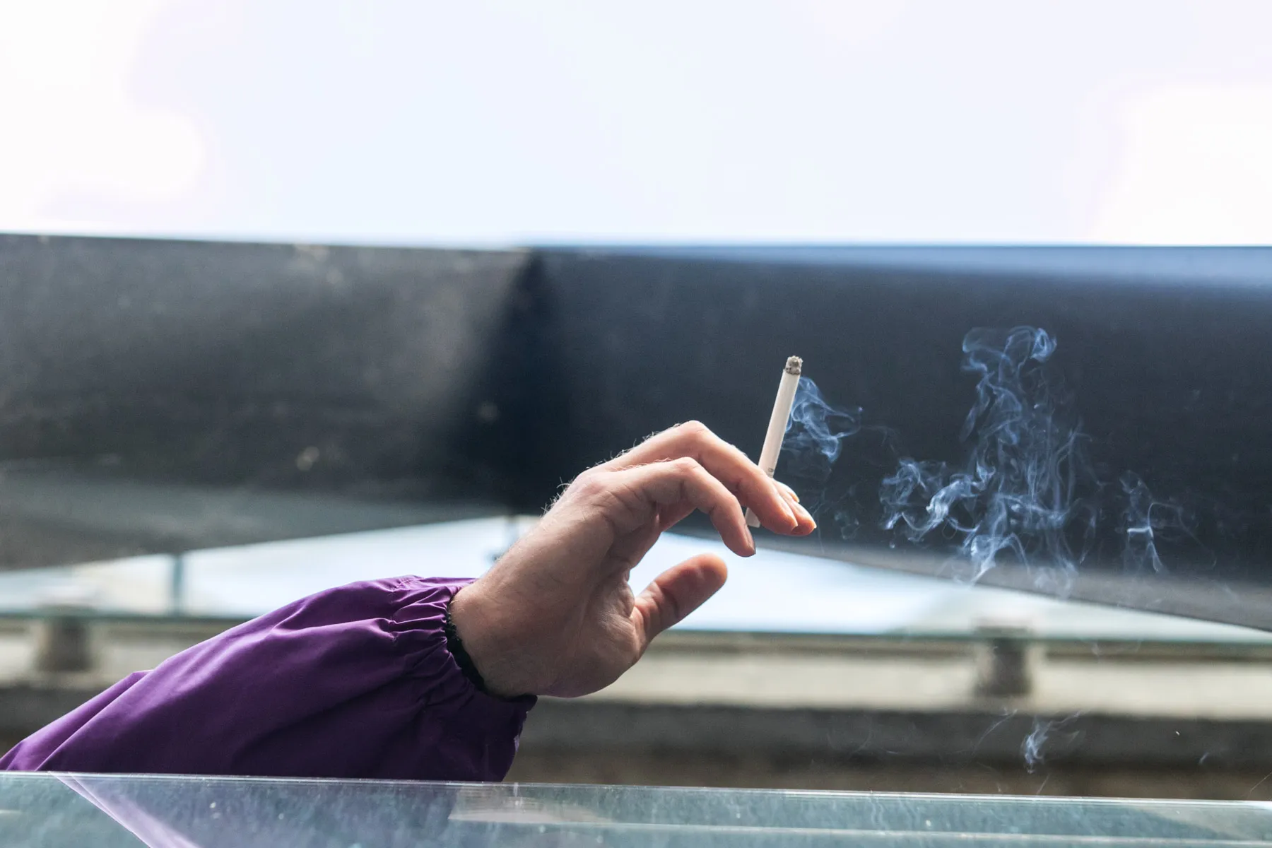 Balkone cigaretę rūkantis žmogus