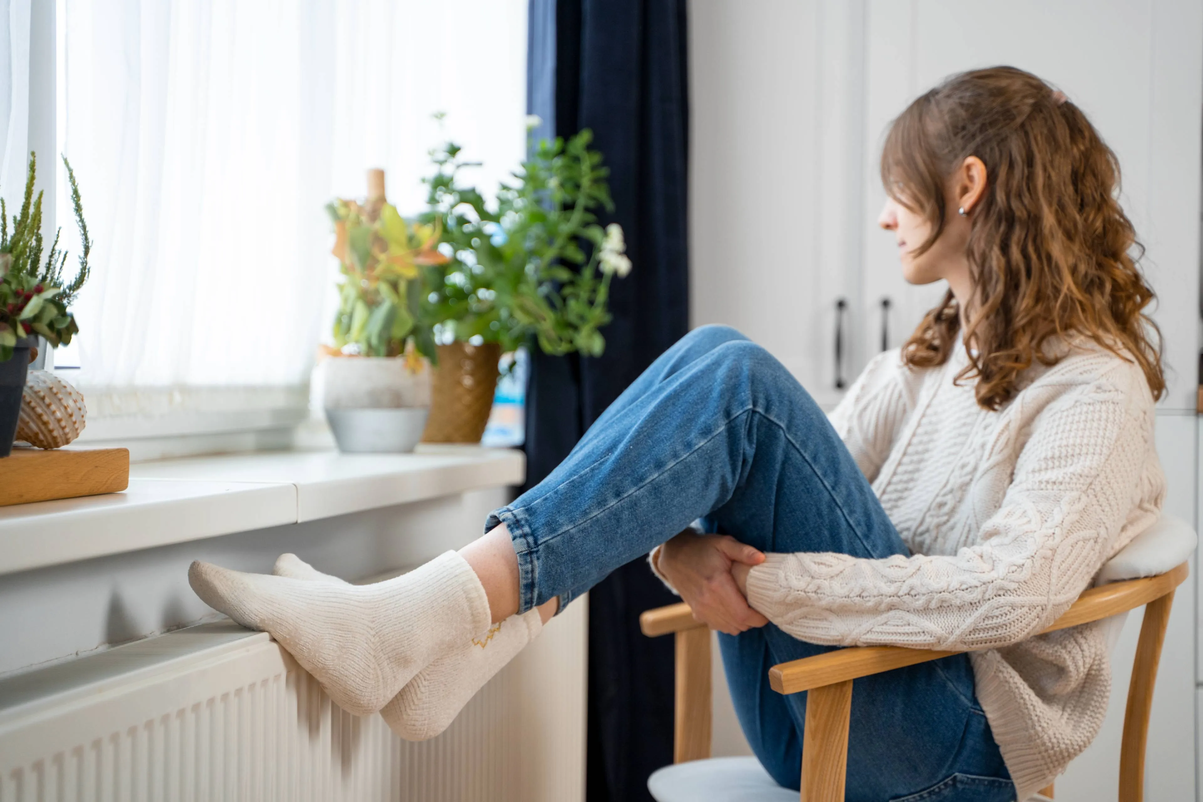full-shot-woman-sitting-near-heater
