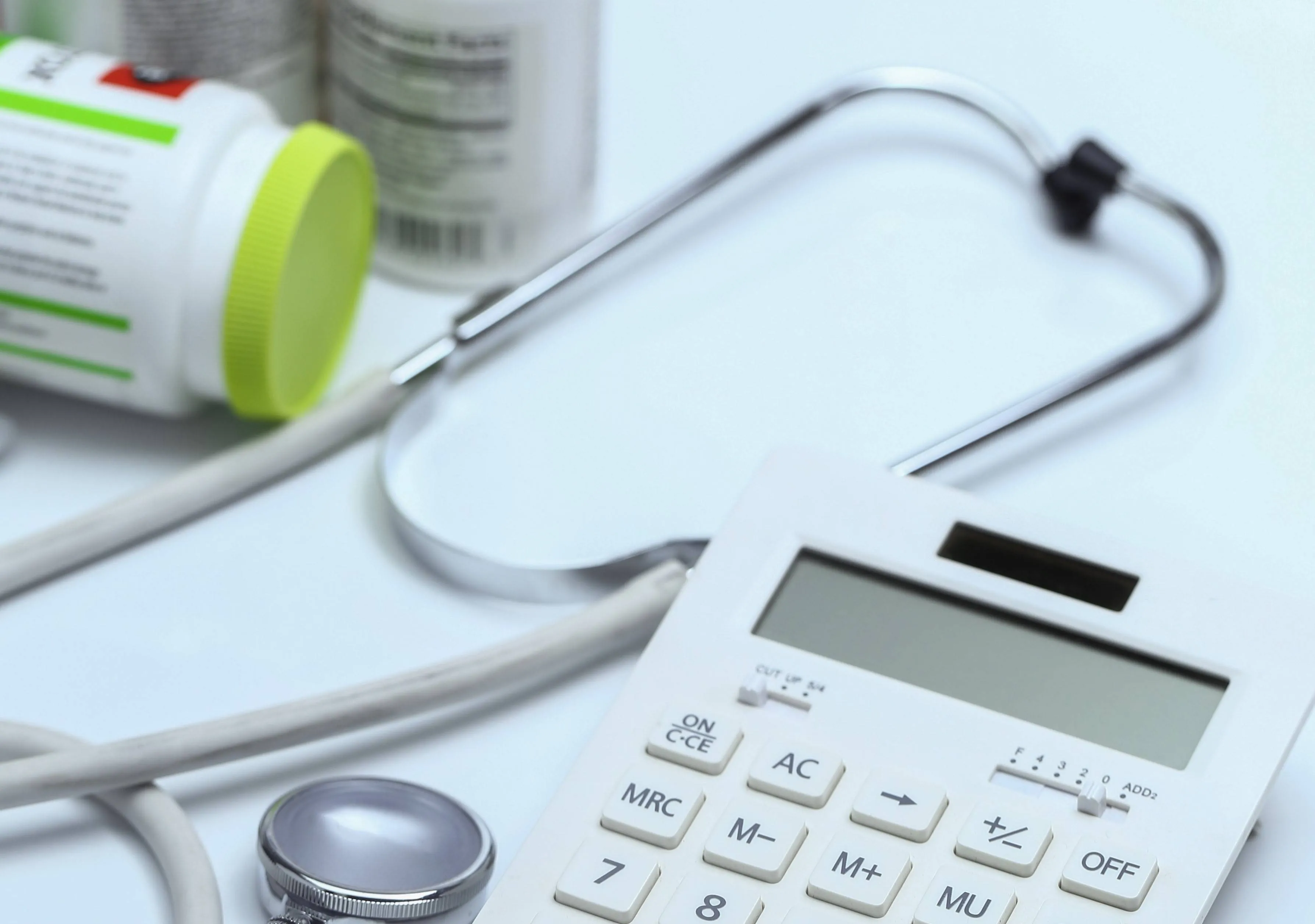 calculator-stethoscope-medicine-bottles-white-background