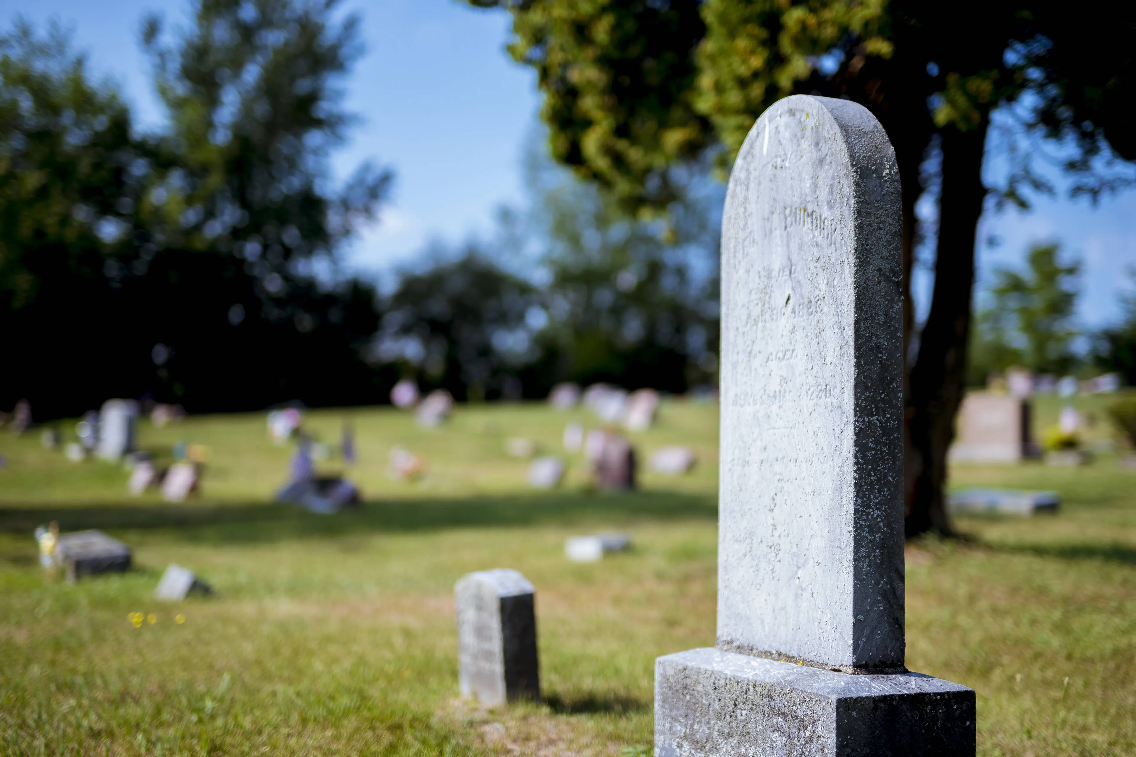 closeup-shot-gravestone-with-blurred-background-daytime