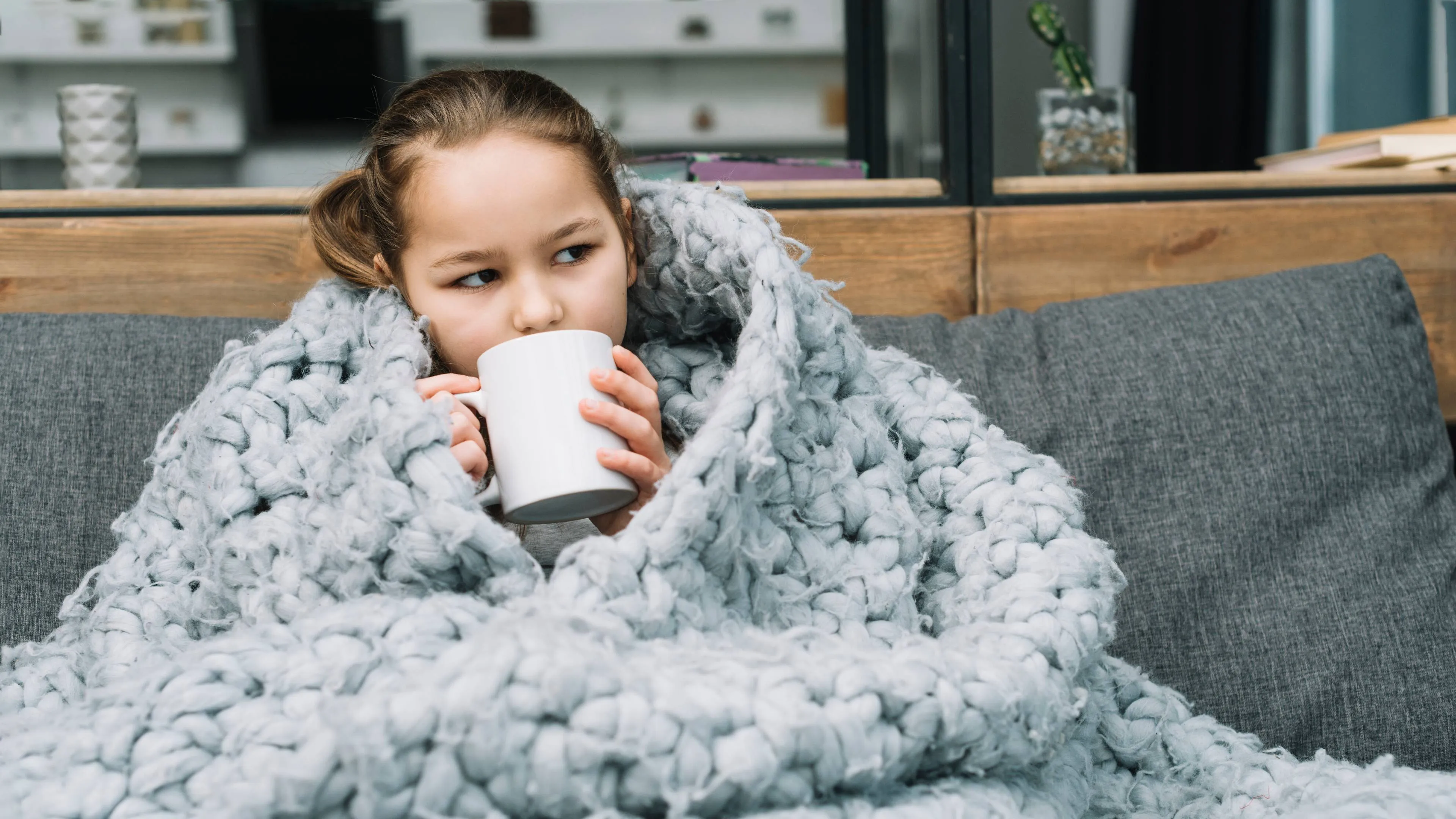 sick-woman-covering-woolen-scarf-around-her-drinking-coffee-from-mug