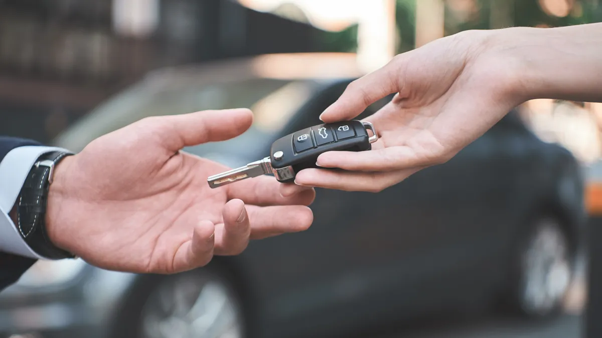 autodealer jonge man die autosleutel ontvangt van verkoopster