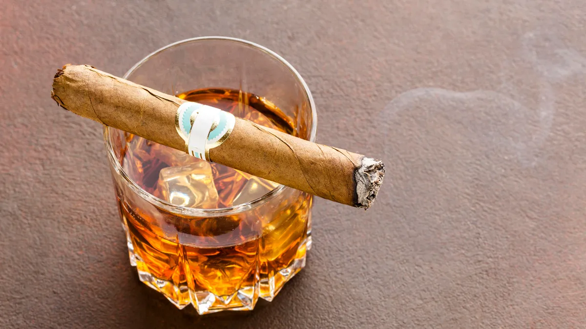 high angle whiskyglas met ijs en sigaar