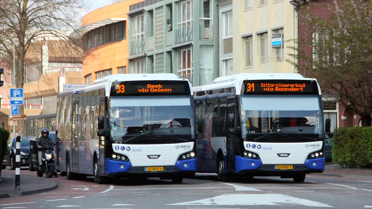 twee bussen van arriva naast elkaar voor het verkeerslicht
