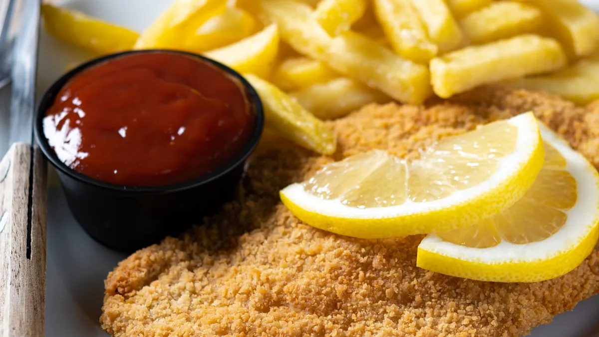 wiener schnitzel met gebakken aardappelen op houten tafel