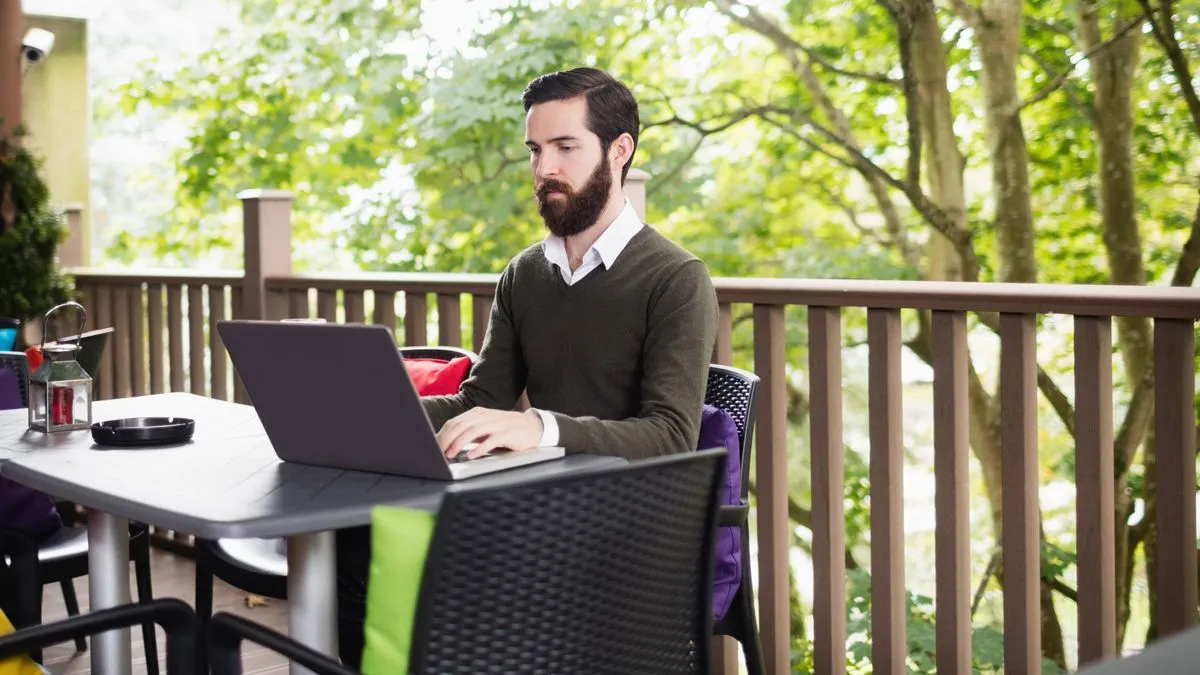 man met laptop werkt thuis op terras