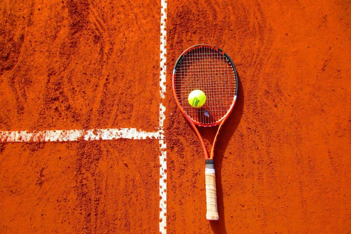 Tennisbold og -ketcher på clay court