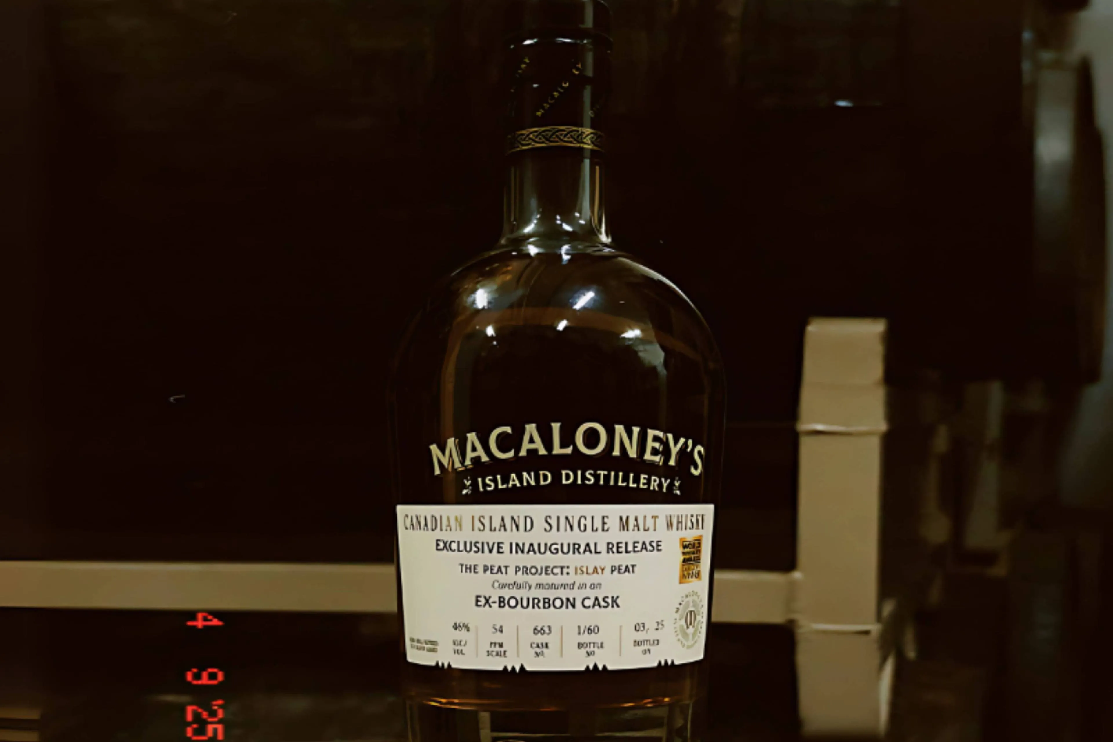 Een fles Macaloneys Island The Peat Project Islay Peat op een vat