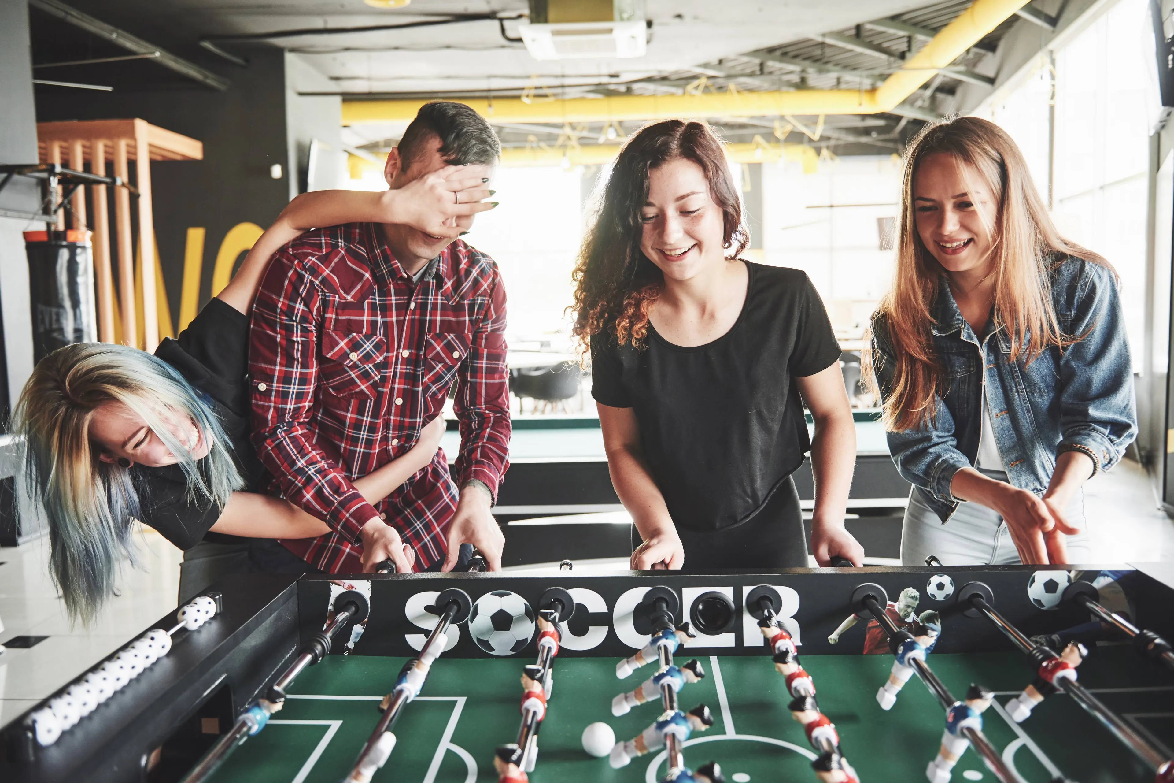 smiling-young-people-playing-table-football-while-indoors
