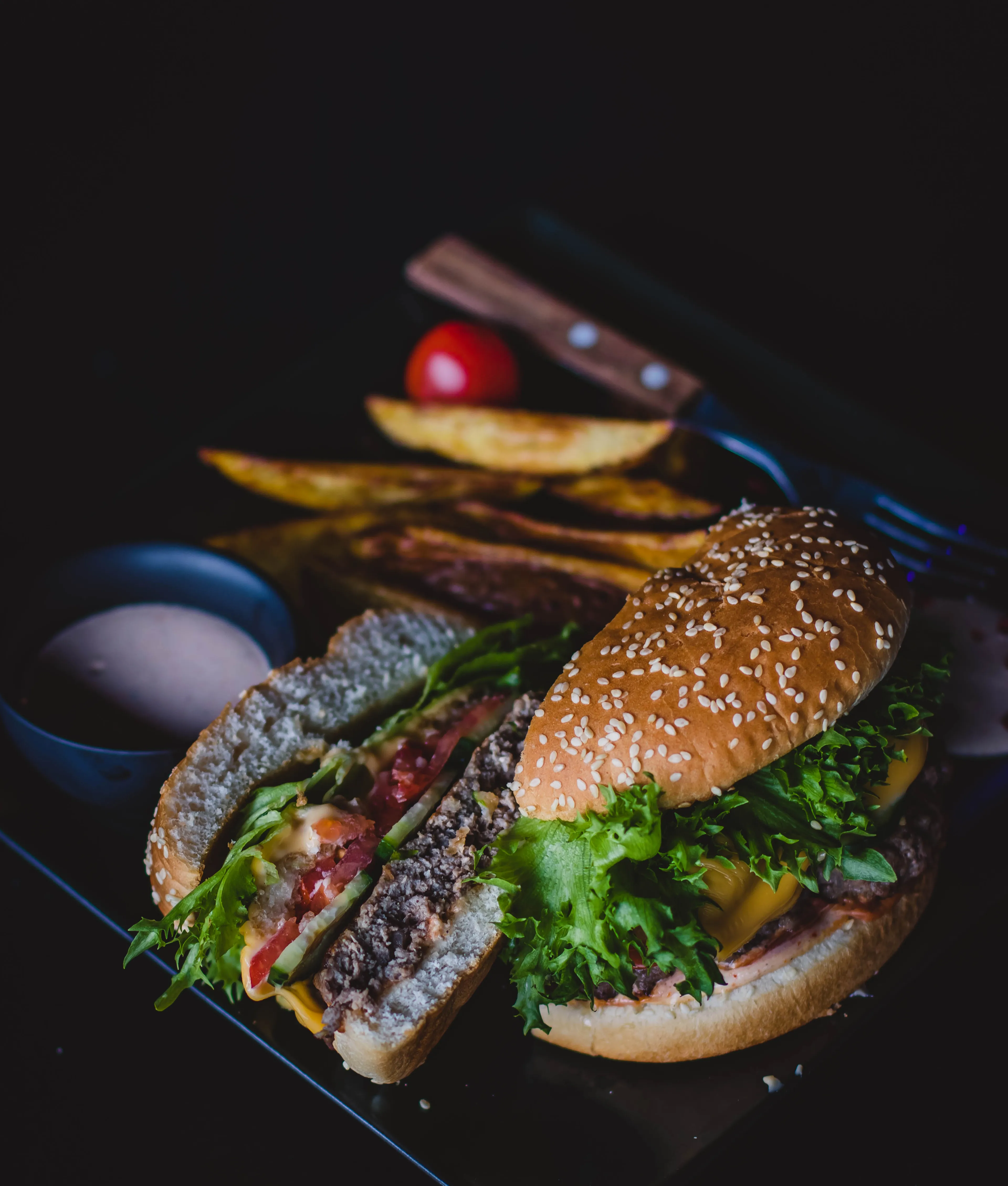 canva burger with green leafy vegetable and cheese on black plate