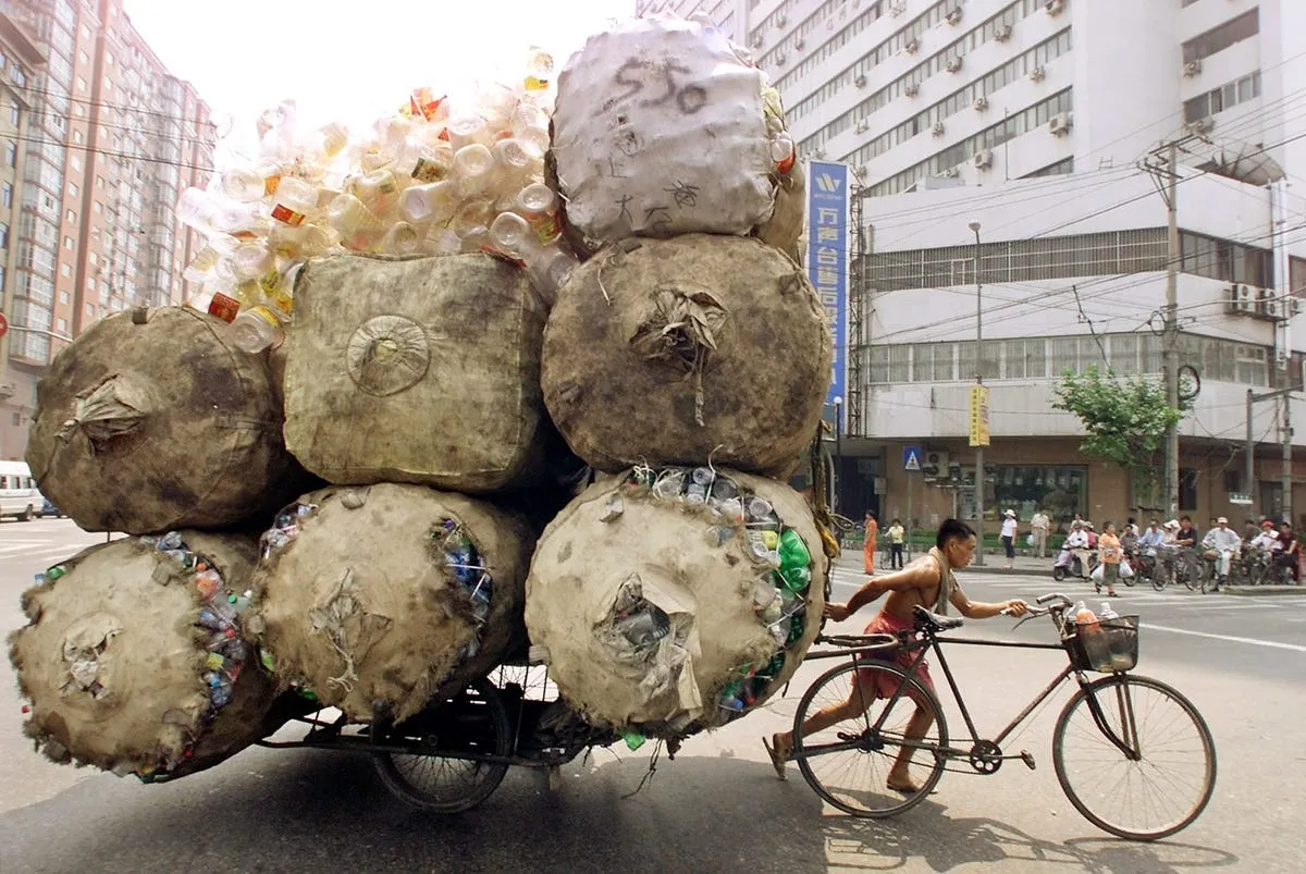 a chinese man pushes a cart loaded with recyclable plastic containers