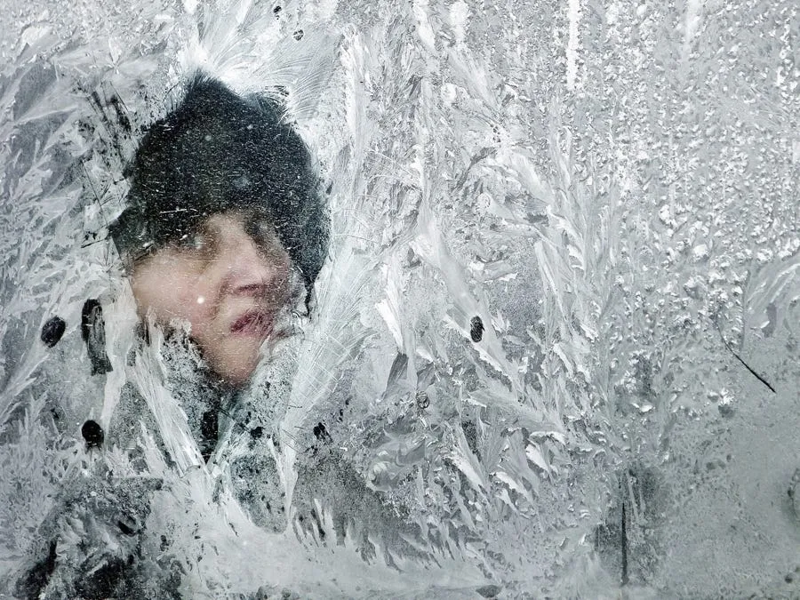 a woman looks through the iced window of a bus in romania
