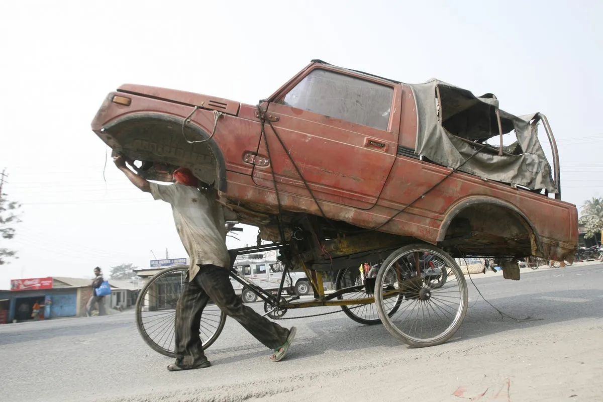 an indian rickshaw driver is taking a wrecked car for a ride