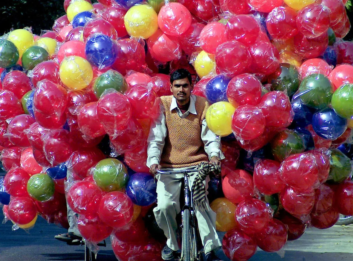 this man in india is biking around with a huge number of plastic balls
