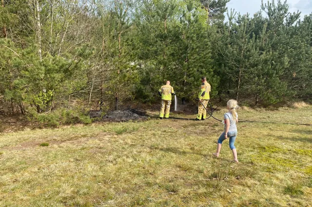Brandweer blust buitenbrand in bosschages bij bosvijver