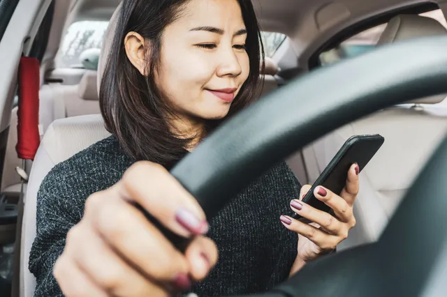 Autorijden met je telefoon op schoot, dat mag gewoon: vrouw hoeft boete niet te betalen