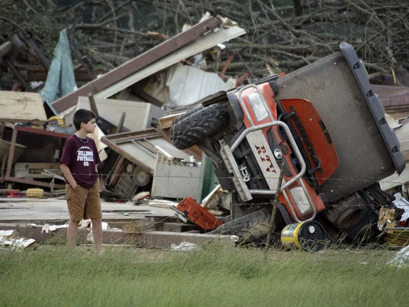 a boy looks at a destroyed home in bond miss