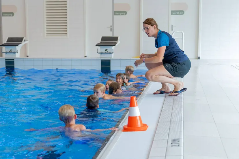 Zweminstructeur geeft kinderen uitleg langs de rand van het bad