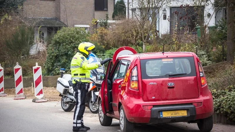 motoragent bij geparkeerde auto