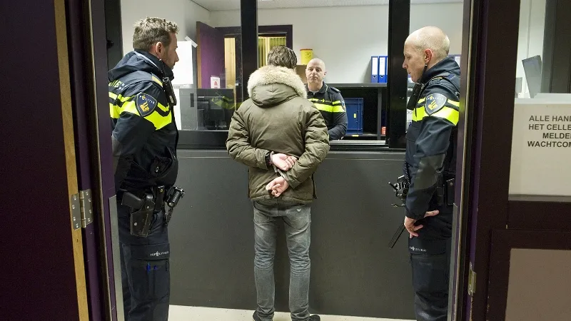 arrestant staat voor politiebalie politie