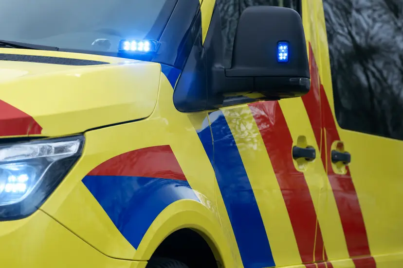 Detail van een gele ambulance met rood-blauwe strepen en blauwe zwaailichten