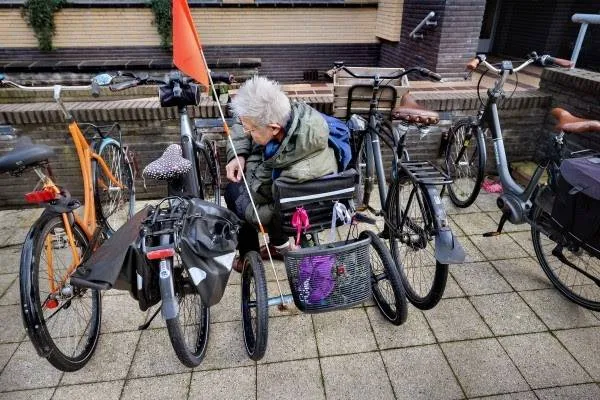 Vrijwilliger Toos van Vliet parkeert haar driewielfiets bij het gemeentehuis in Hilversum. Foto. DigiDaan.