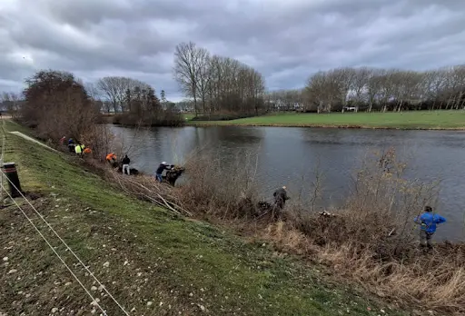 rijwilligers knotten wilgen bij een visvijver in Beuningen