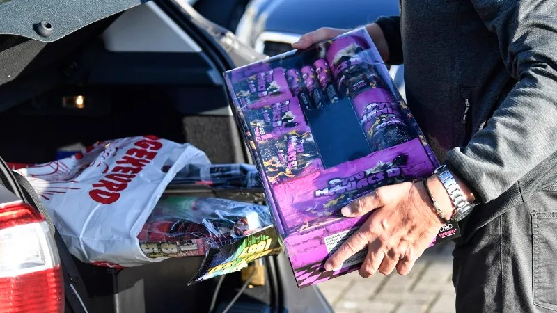 man stopt vuurwerk in achterbak