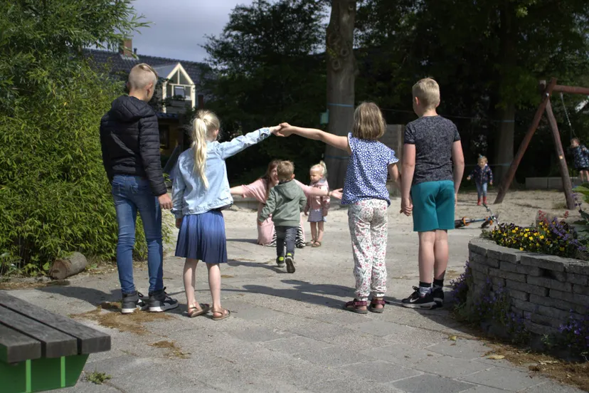 echten foto 2 juf op schoolplein die kind met open armen ontvangt