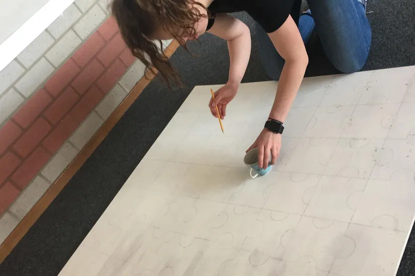 foto lastisha anouschka aan het werk met de puzzelstukken uittekenen