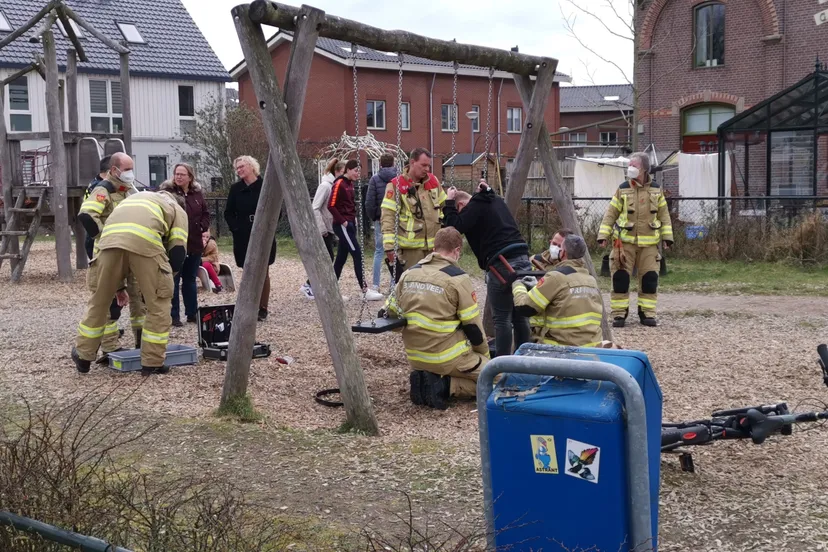 man beknelt op speeltoestel