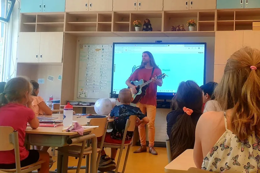 showkorpsen irene trakteren basisscholen op muziekles foto beschrijving meester dennis met gitaar voor de klas